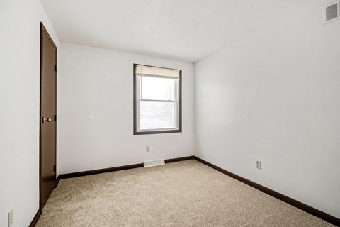 A room with a window and carpeted floor.