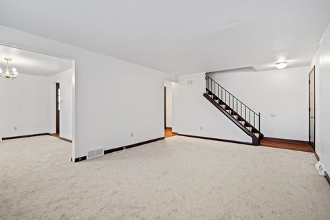 A spacious room with a staircase and a chandelier.