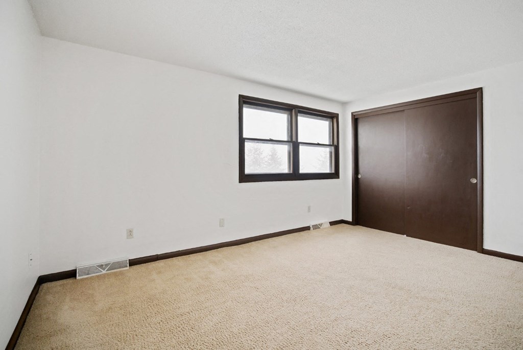 A room with a brown door and a window with a white frame.