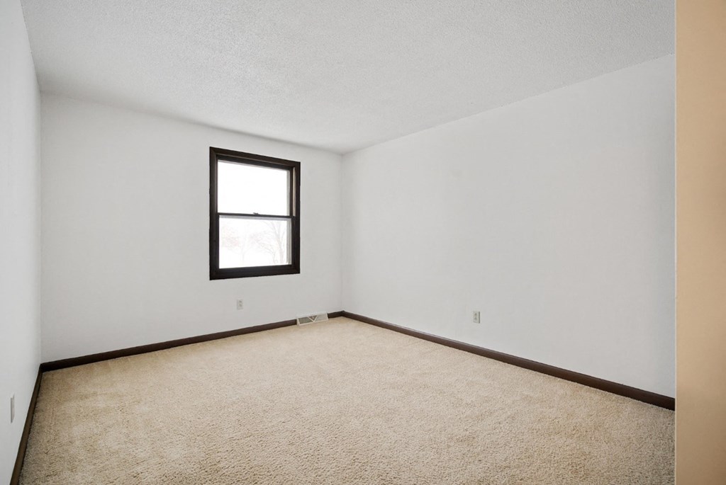 A room with a carpeted floor and a window.