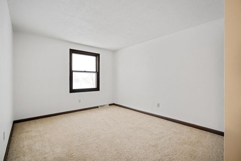 A room with a carpeted floor and a window.