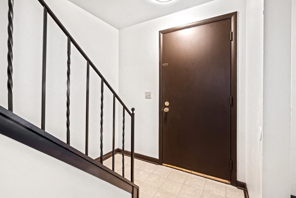 A brown door is at the end of a hallway.