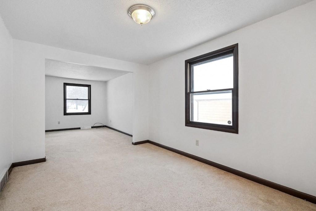 A room with a carpeted floor and two windows.