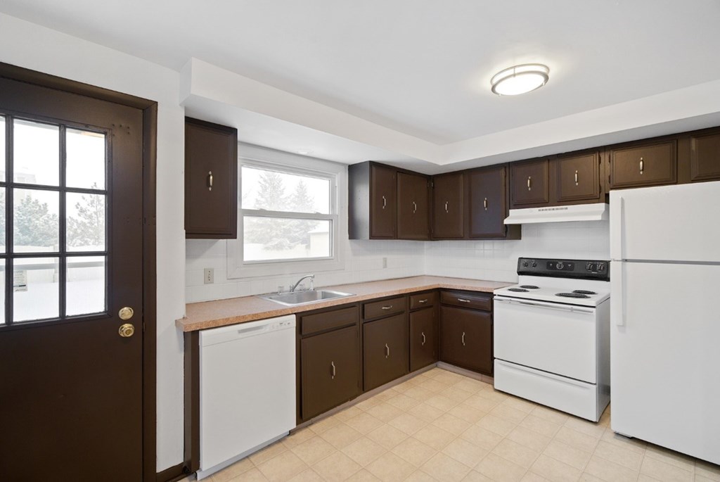 A kitchen with brown cabinets and white appliances.