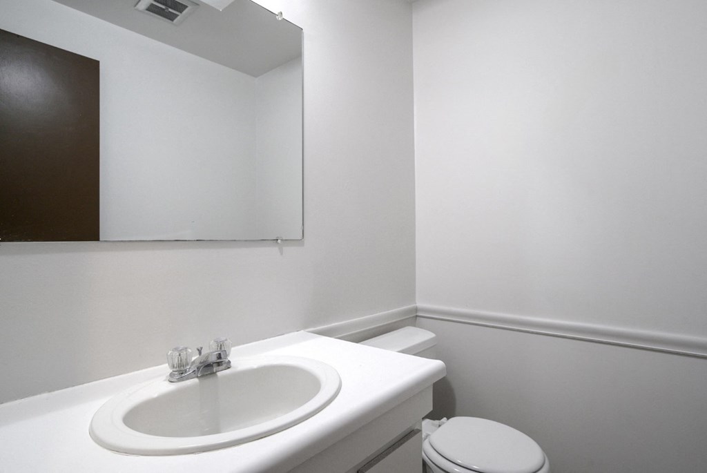 A white sink in a bathroom with a toilet in the corner.