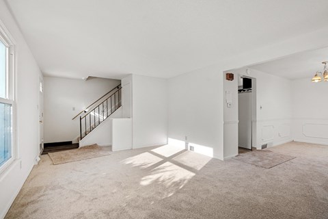 A spacious, empty room with a staircase and a window.