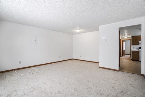 A spacious room with white walls and carpeted floor.