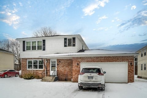 A white car is parked in front of a house.