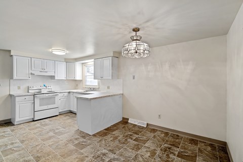 A kitchen with white cabinets and a tiled floor.