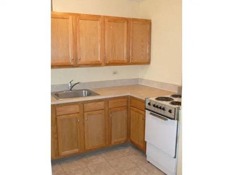 A kitchen with wooden cabinets and a white stove.