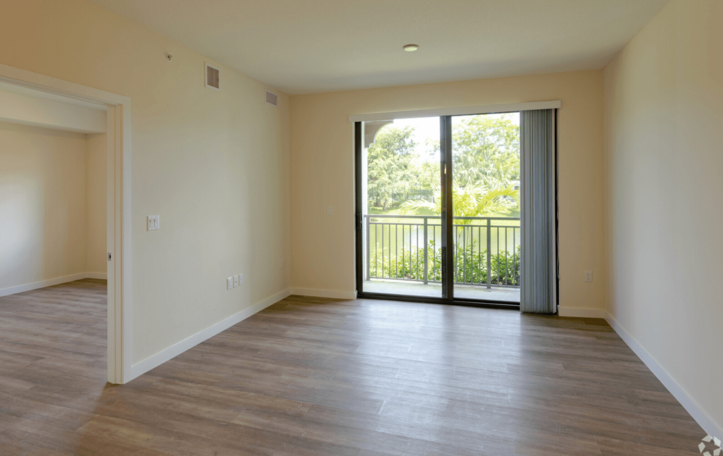 an empty living room with a sliding glass door leading to a balcony