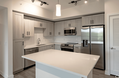 a white kitchen with stainless steel appliances and white counter tops