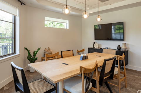 a conference room with a large wooden table and chairs and a flat screen tv on the wall