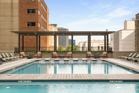 A pool with a wooden deck and lounge chairs.