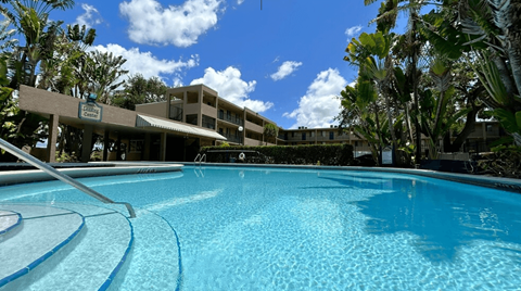 A large swimming pool in front of a building with trees around.