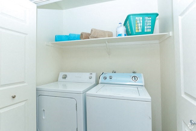 a white laundry room with two washes and a dryer