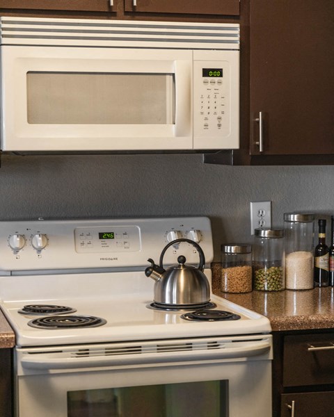 a kitchen with a stove and microwave and a tea kettle on the stove
