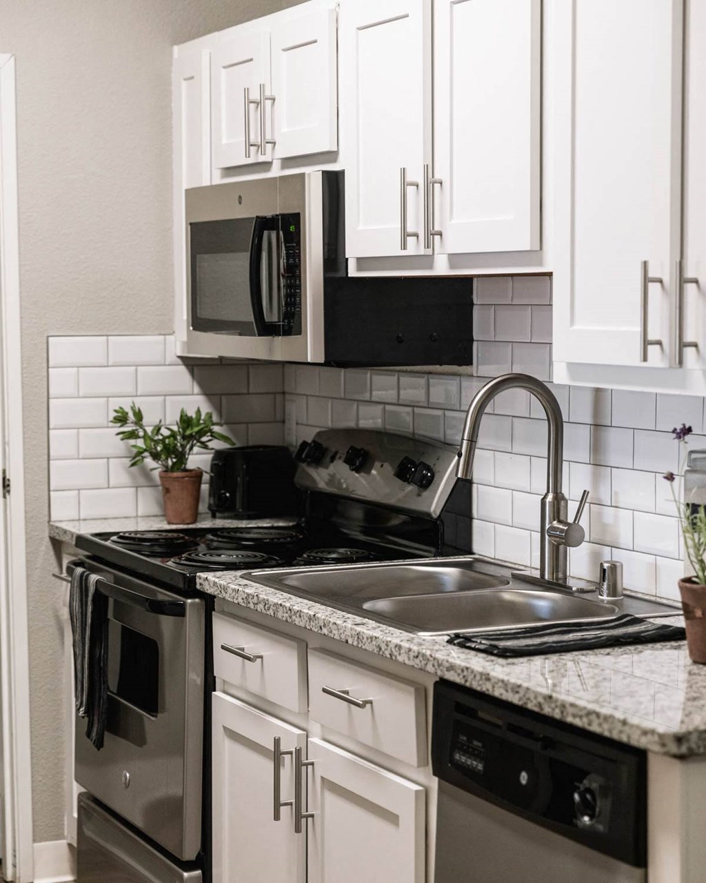 a kitchen with white cabinets and a sink and a microwave