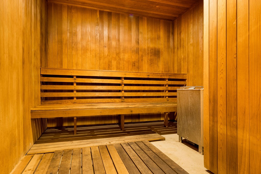 a wooden sauna with a wooden bench and a trash can