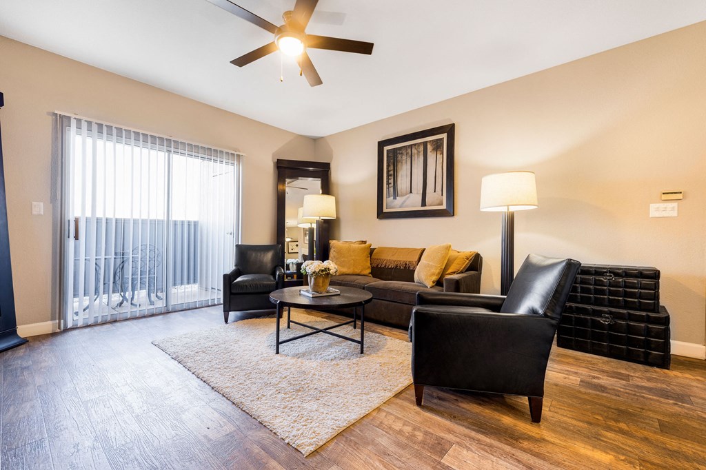 a living room with leather furniture and a ceiling fan
