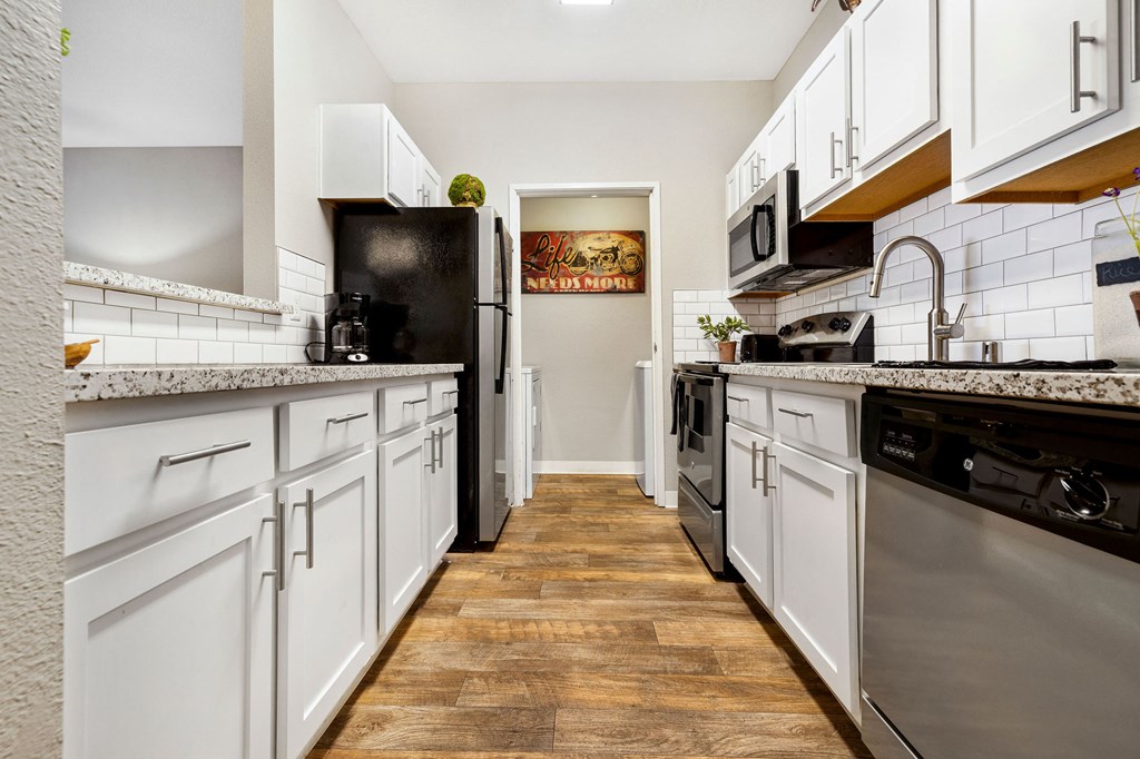 a long kitchen with white cabinets and stainless steel appliances
