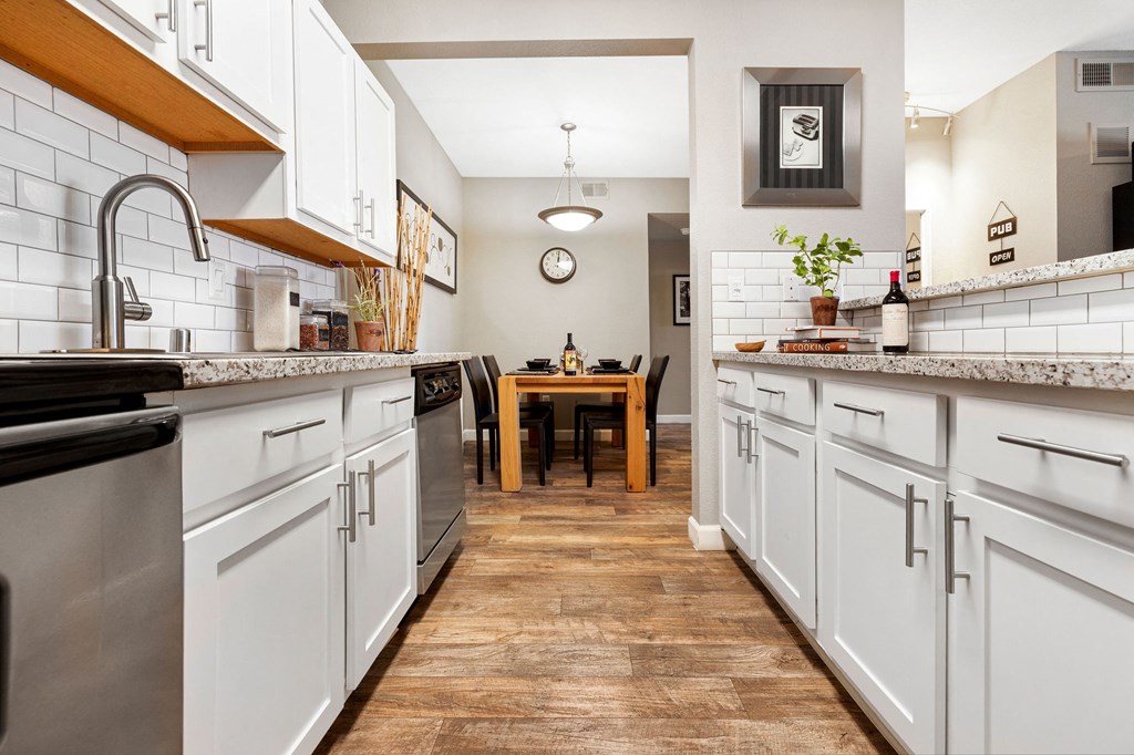 a kitchen with white cabinets and stainless steel appliances and a dining room table
