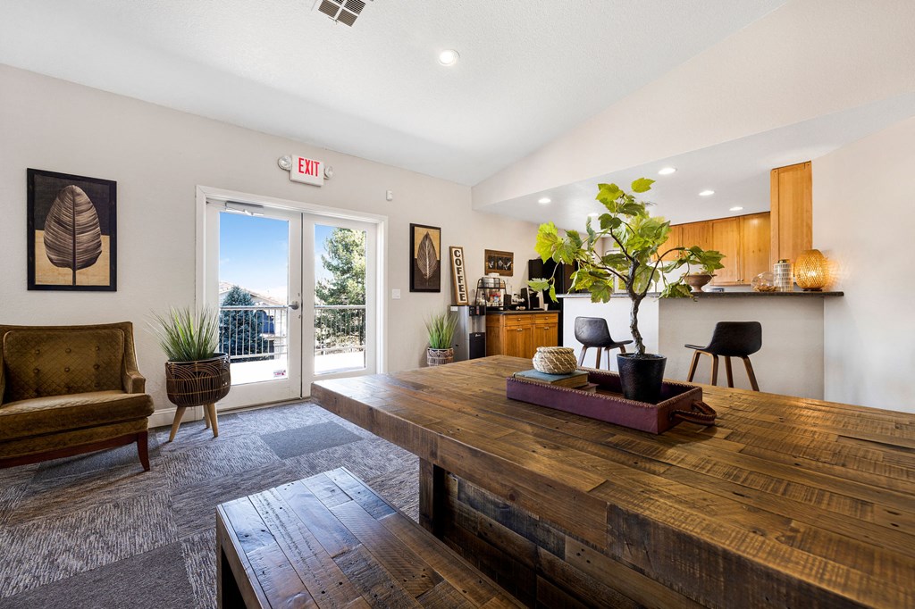the living room with a large wooden table and a kitchen in the background