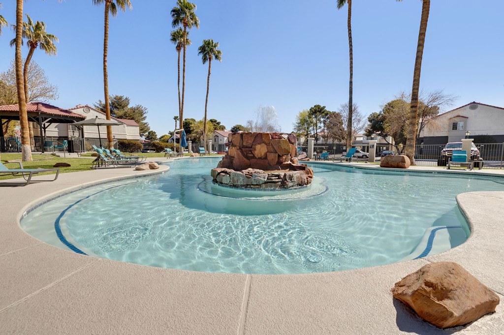 a resort style pool with a fountain and palm trees