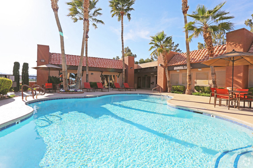 a large swimming pool in front of a house with palm trees