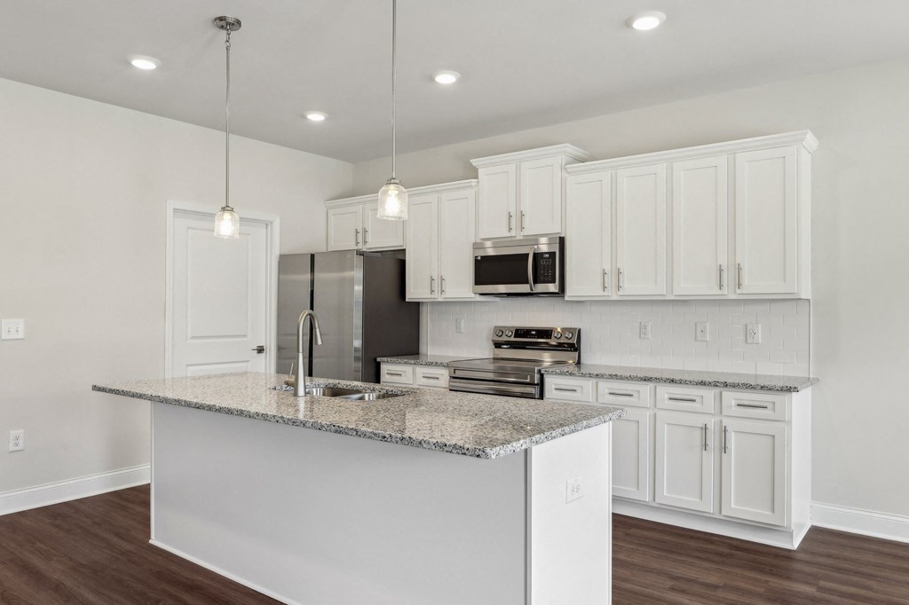 Sleek kitchen with white cabinetry and granite countertops.