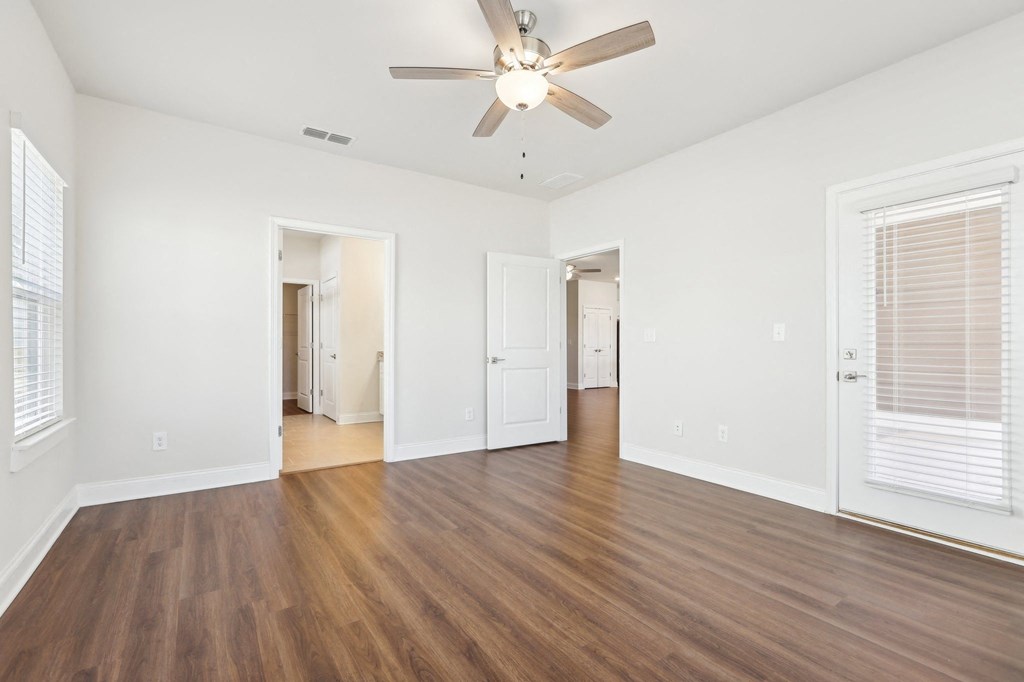 Bright bedroom featuring wood floors and a ceiling fan.