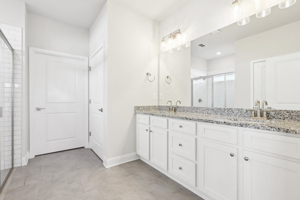 Primary bathroom with double vanity, walk-in shower and walk-in closet.