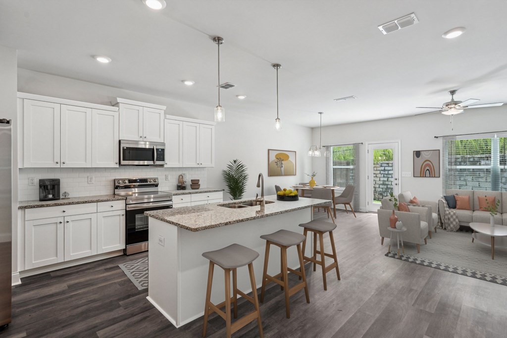A modern kitchen showcasing a granite countertop island with bar seating and premium stainless steel appliances.