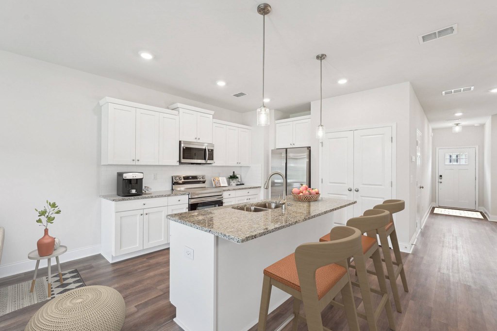 A modern kitchen showcasing a granite countertop island with bar seating and premium stainless steel appliances.