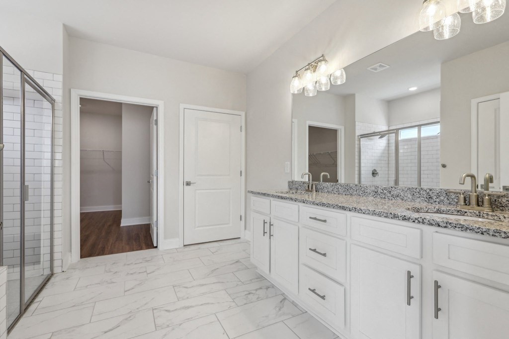 Primary bathroom with double vanity, walk-in shower and walk-in closet.