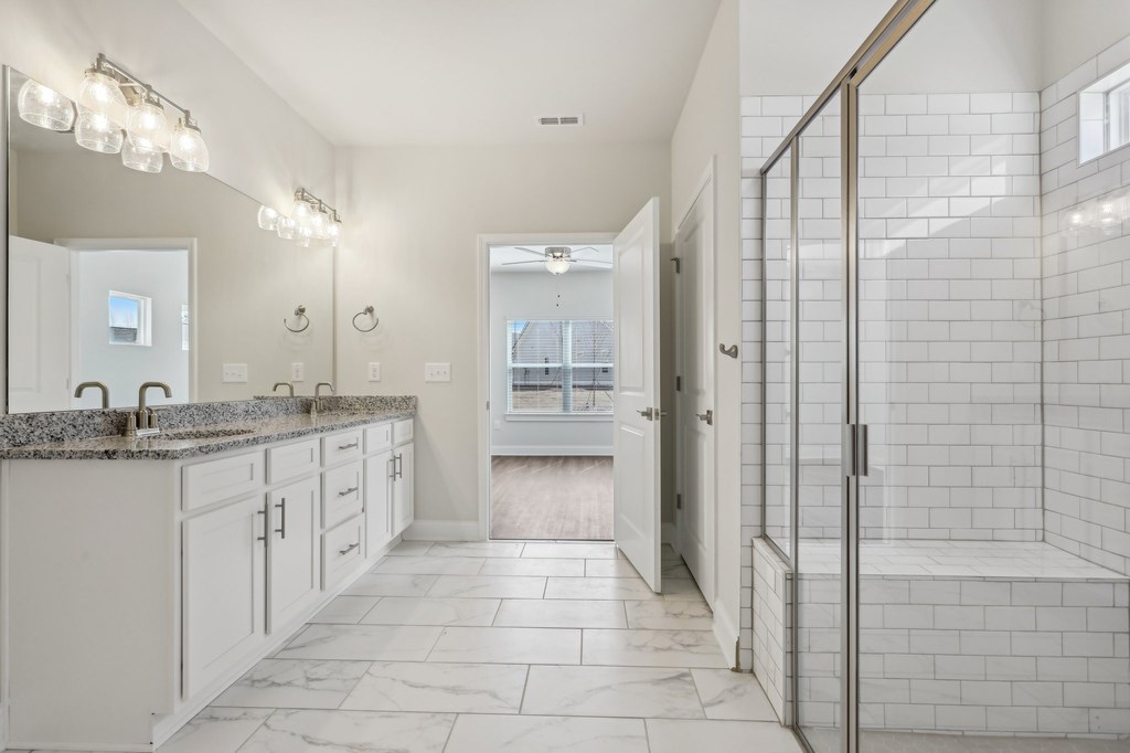 Luxurious primary bathroom featuring a double vanity, walk-in shower, and spacious walk-in closet.