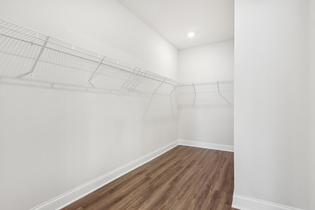 Primary suite with a full walk in closet featuring custom racks.