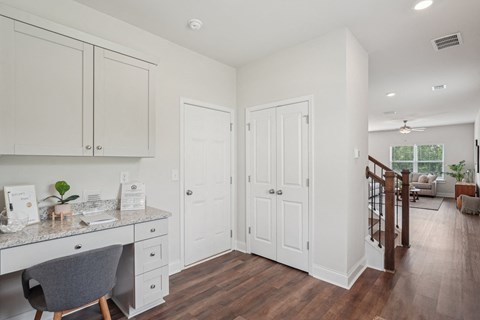 A kitchen with white cabinets and a desk with a chair.