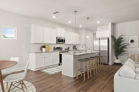 an open kitchen and living room with white cabinets and a bar with stools