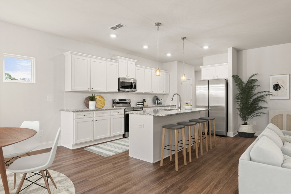 an open kitchen and living room with white cabinets and a bar with stools