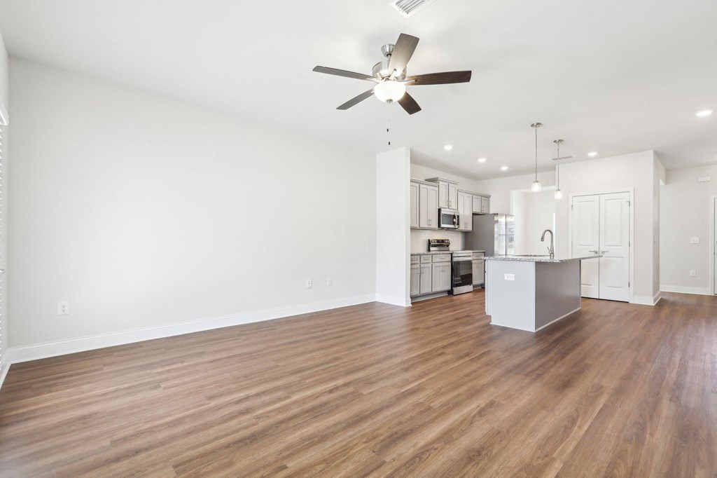 Spacious kitchen equipped with a refrigerator, sink, and ceiling fan.