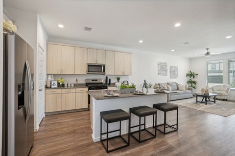 a kitchen and living room with a large island with three stools