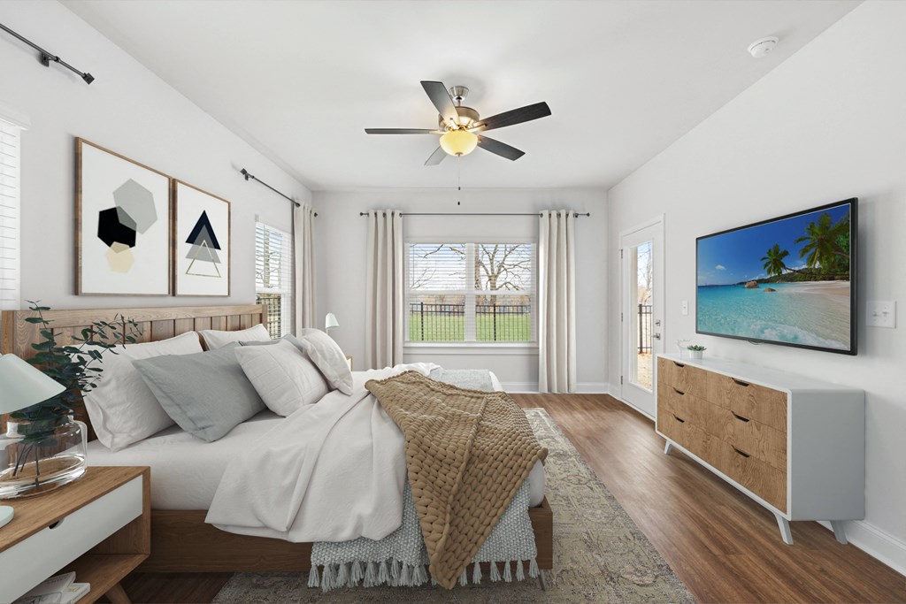Another perspective view of the serene primary suite, showcasing a modern ceiling fan, sleek entertainment, and sunlit window views.