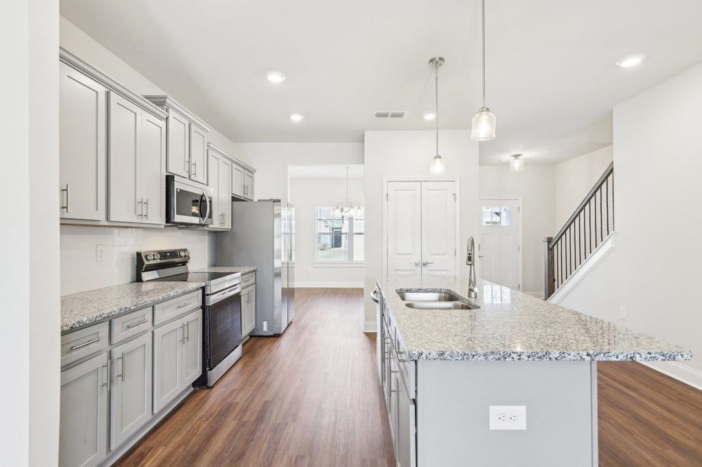 Modern kitchen with white cabinets and granite countertops, flowing seamlessly to the staircase.