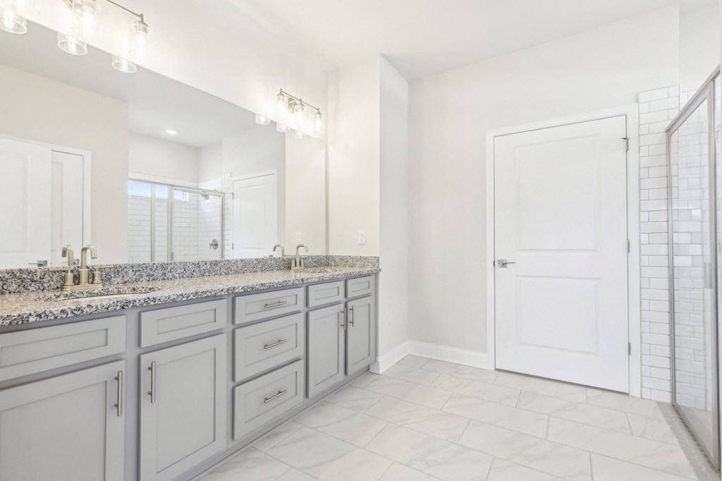 Luxurious primary bathroom featuring a double vanity, walk-in shower, and spacious walk-in closet.
