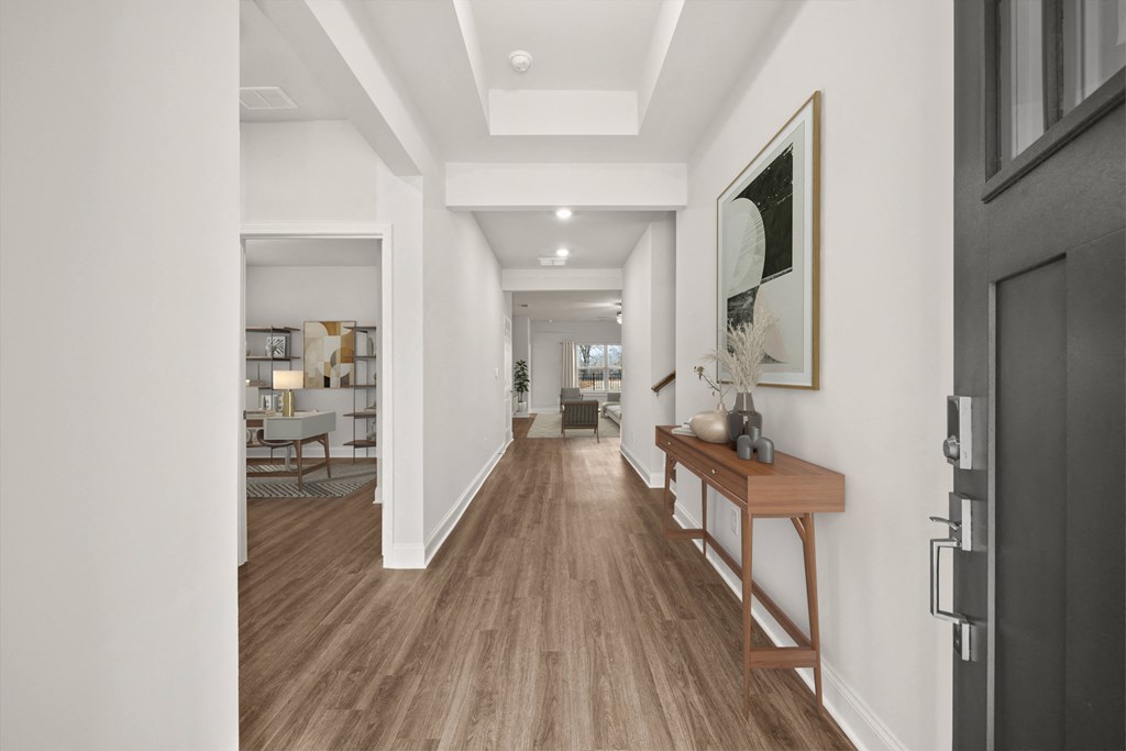 a hallway with a wood floor and white walls and a door