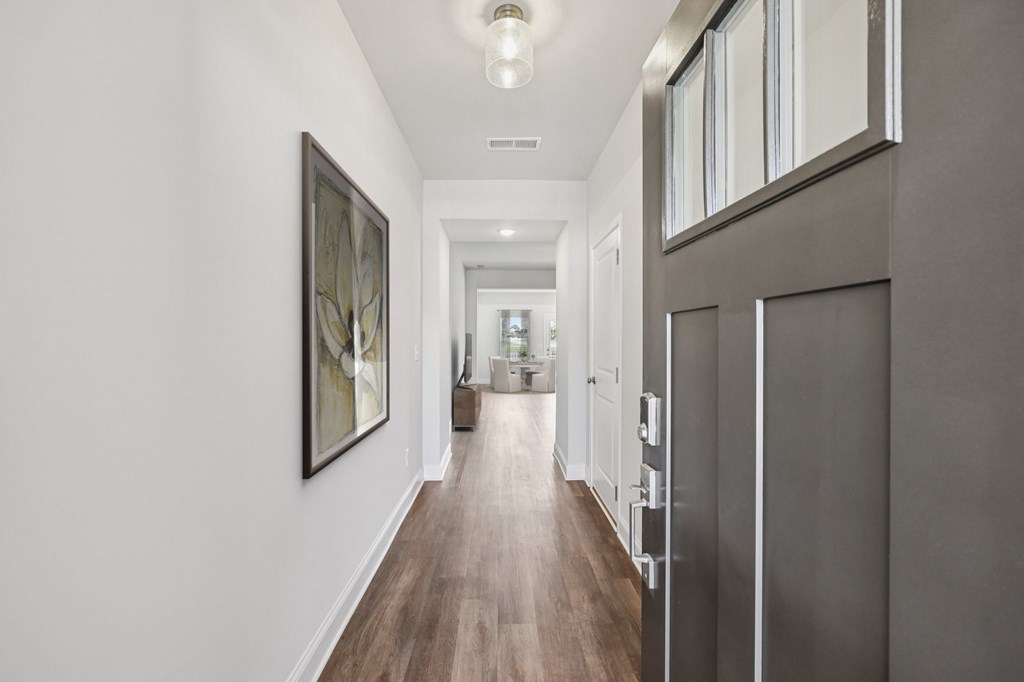 The entrance to the Stafford home featuring rich hardwood-style flooring and crisp white walls.