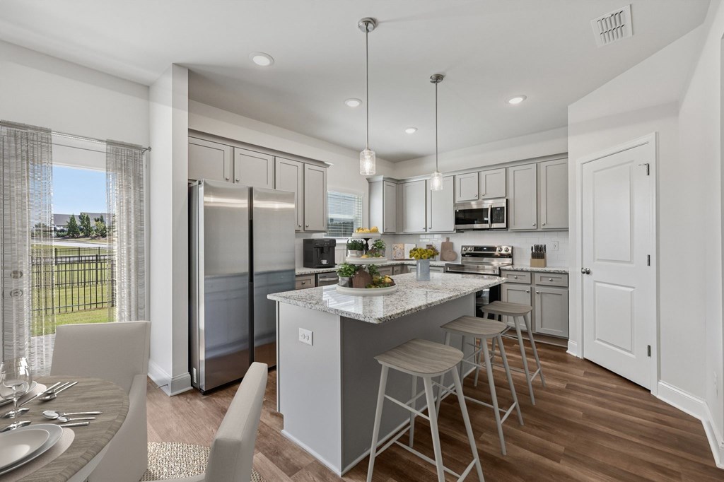 A modern kitchen showcasing a granite countertop island with bar seating and premium stainless steel appliances.