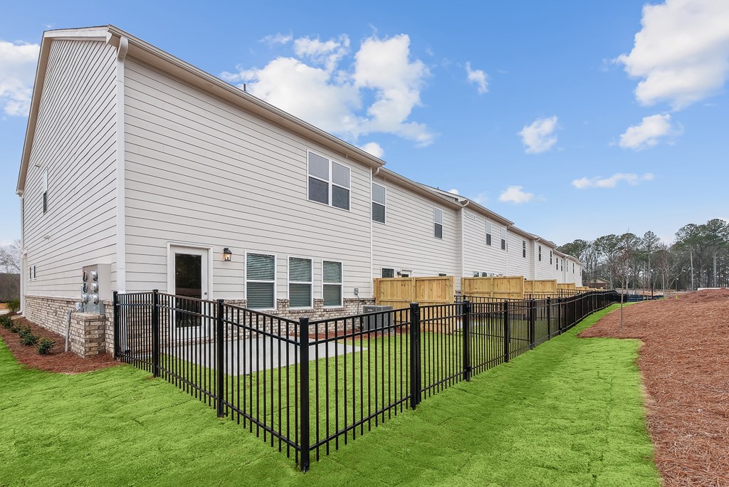 the exterior of a building with a yard and a fence