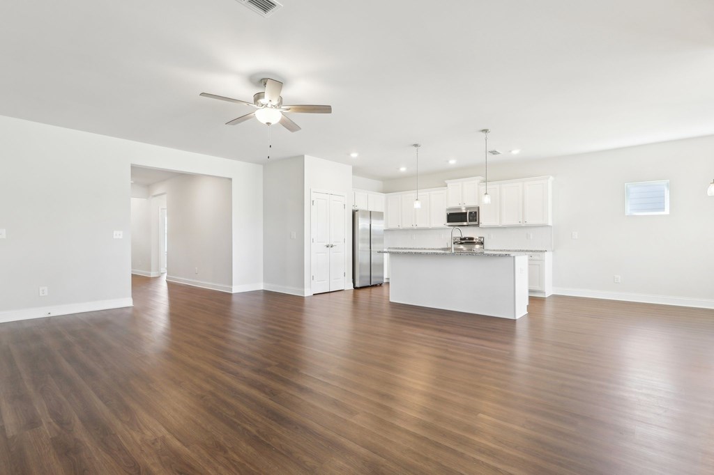 A spacious room with wooden floors and a ceiling fan.